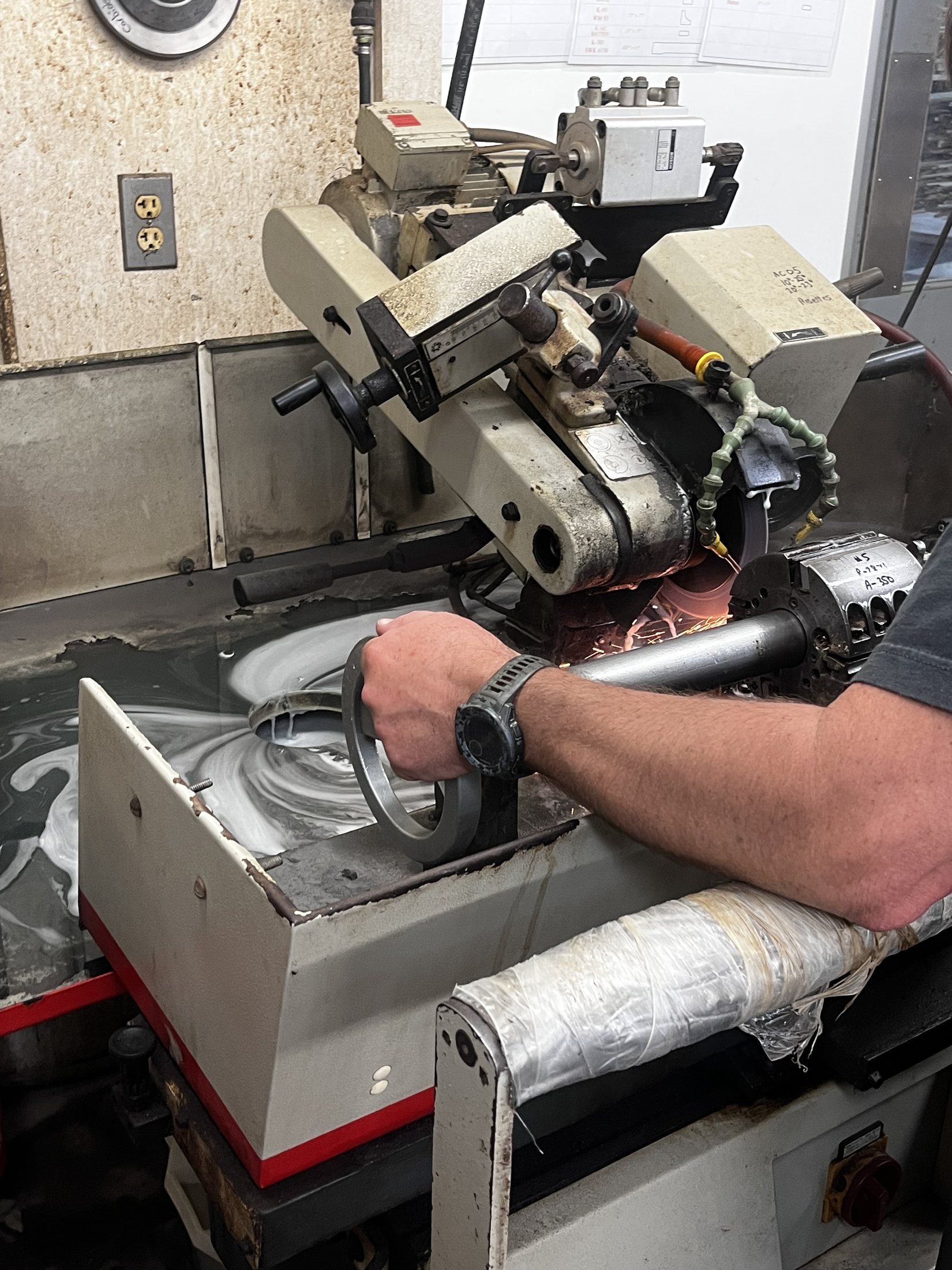 Operator adjusting a handwheel on an industrial grinding machine during an active test.