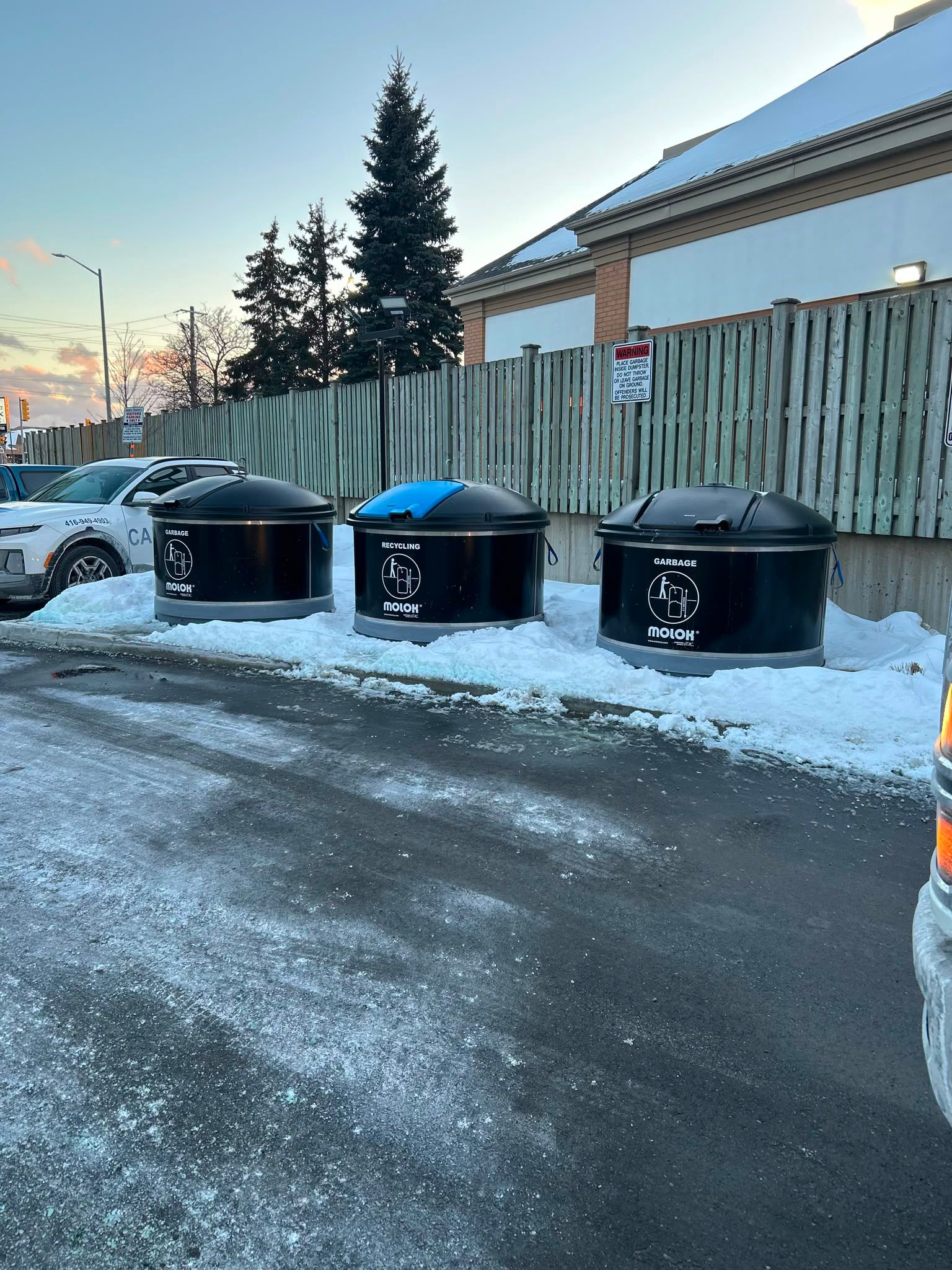 Three black Molok semi in-ground garbage and recycling bins installed at a winter property