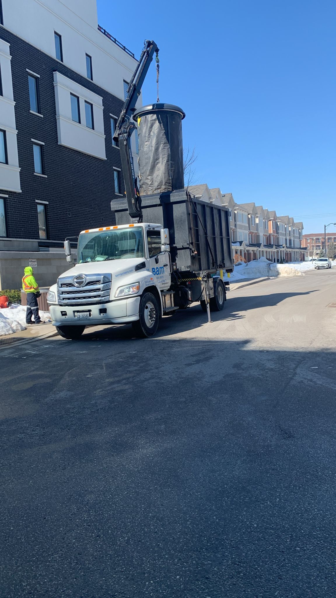 Bam Quick Bins crane truck lifting a Molok collection bag at a townhouse complex