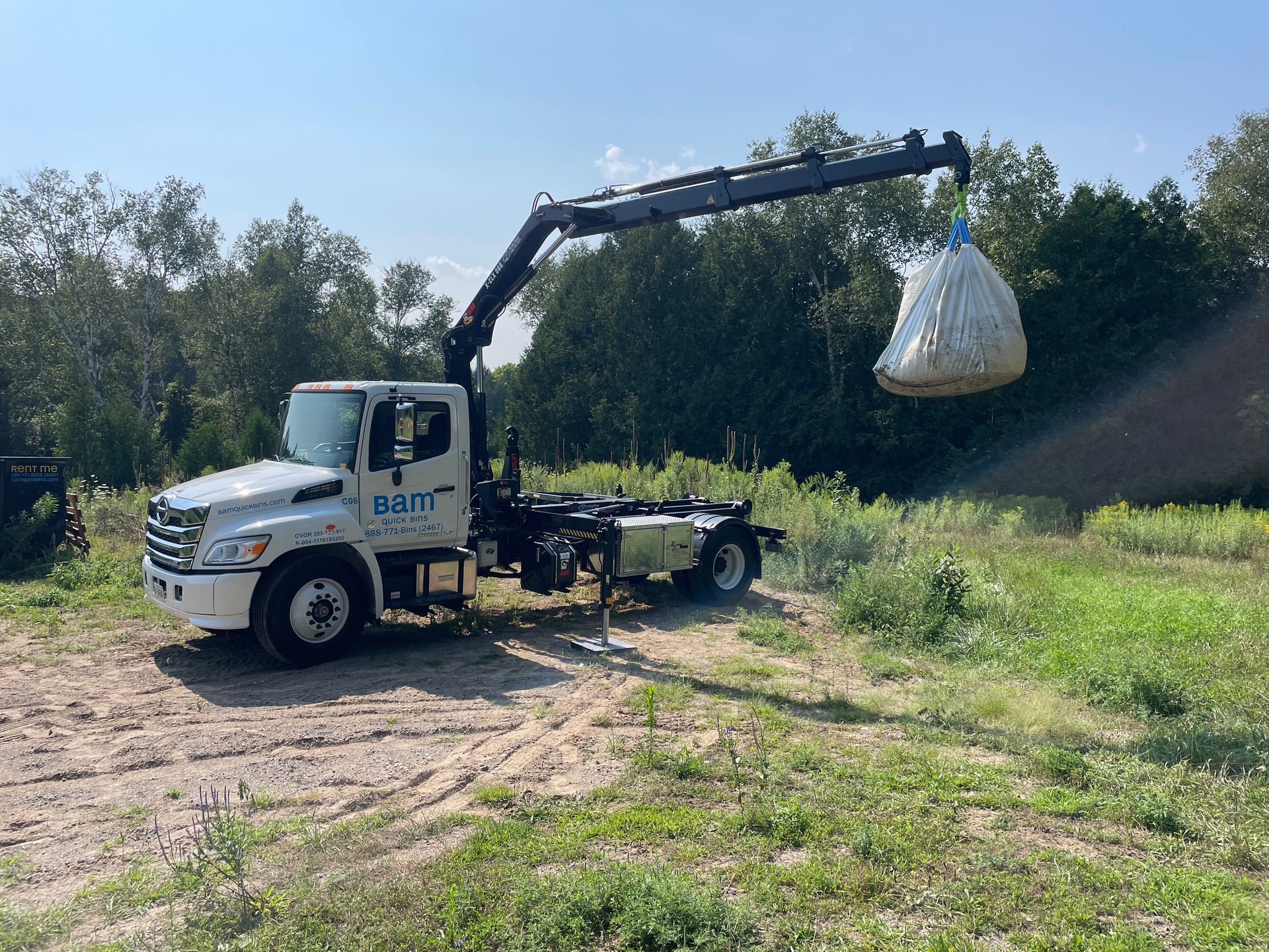 Bam Quick Bins crane truck lifting a full white one tonne Bam Bag off a job site