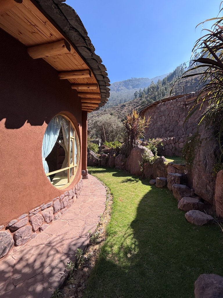 Earthen casita with a round window beneath the Andean mountains