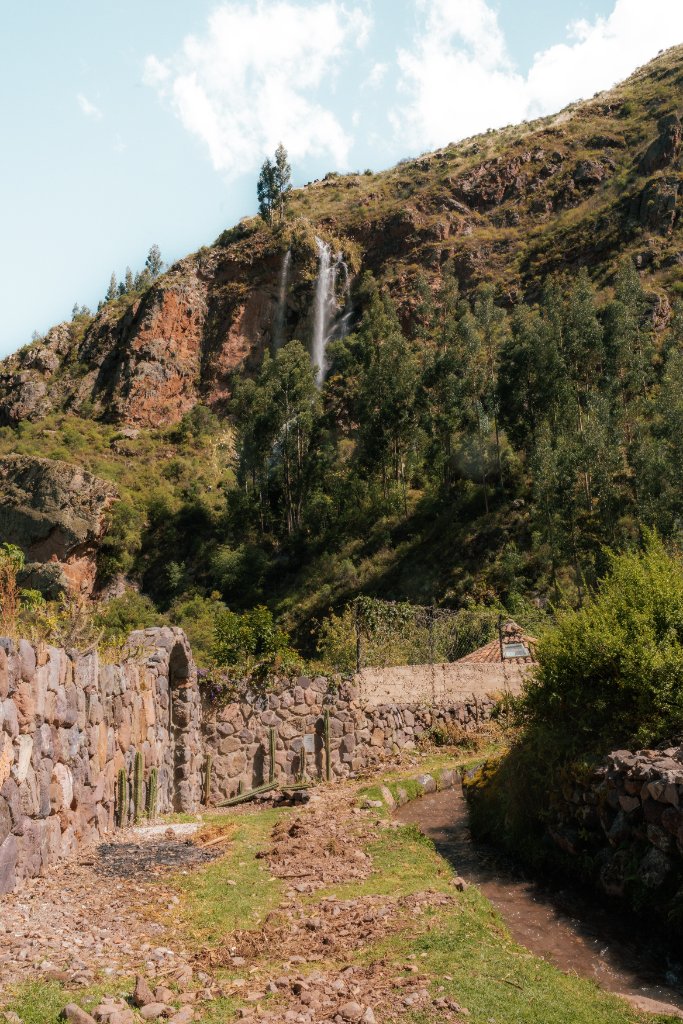 A mountain path and waterfall beneath the Sacred Valley peaks