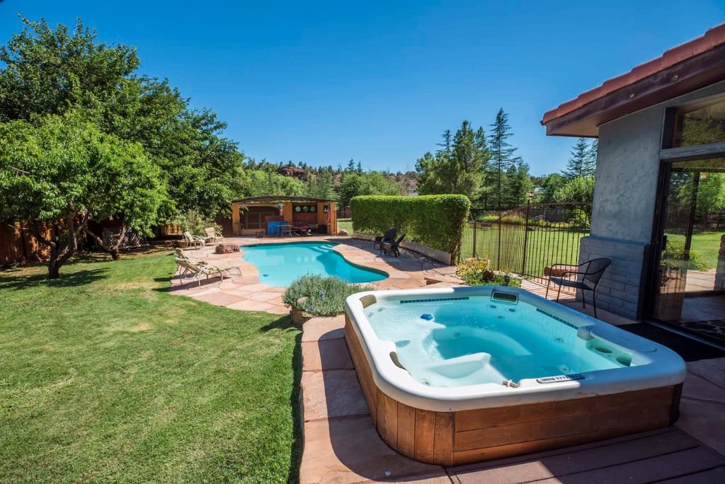 Outdoor pool and hot tub surrounded by green lawn