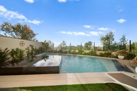 Outdoor kitchen and lounge area beside a custom Irvine pool