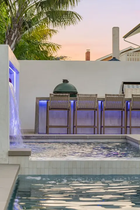 Sheer-descent waterfall flowing into a custom gunite pool in Huntington Beach, California