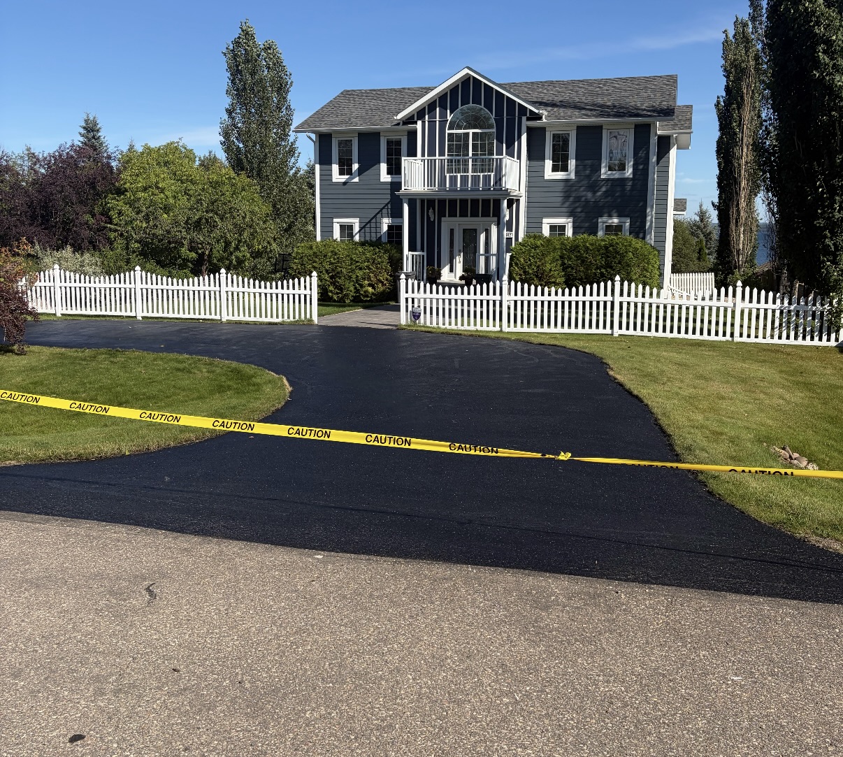 Front-facing view of the sealed driveway and home, after oil-based sealant