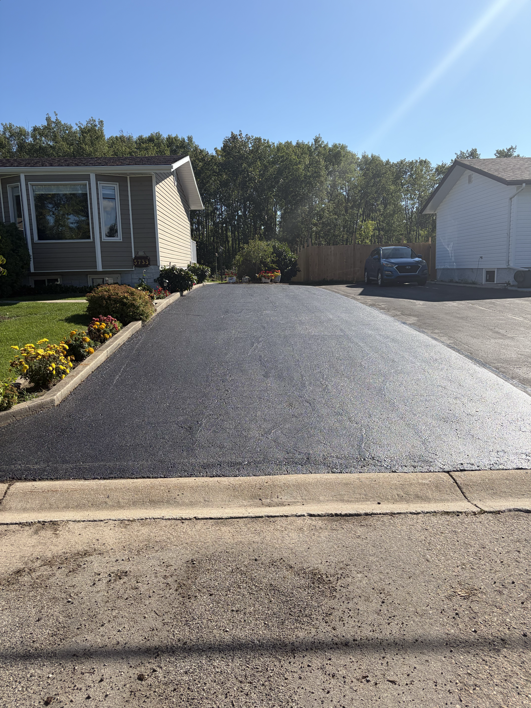 Long driveway with a rich, uniform black finish after oil-based sealant