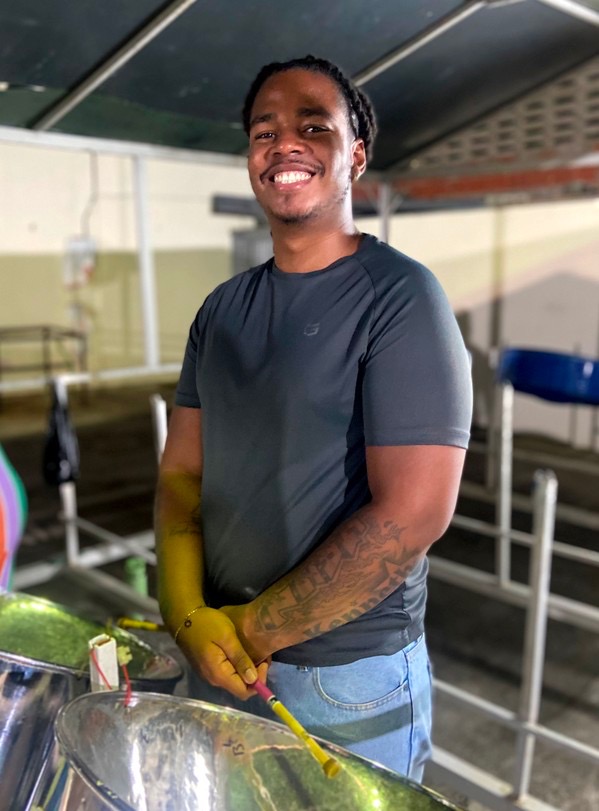 Kobie Alleyne smiling at the panyard, lanyard around his neck