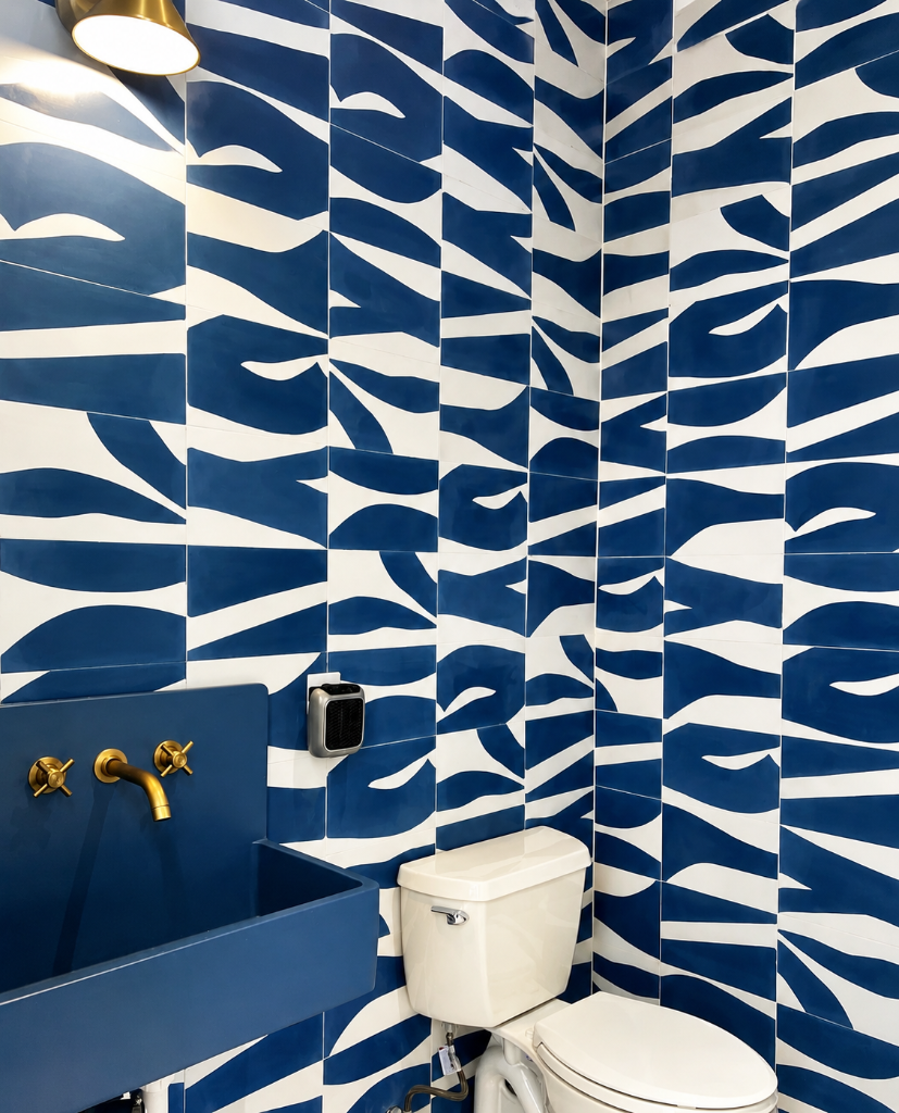 Bold zebra-patterned blue and white tile wall with a matching deep blue wall-mounted sink, brass cross-handle faucet, and brass wall sconce