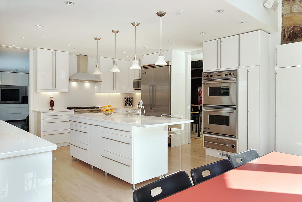 Modern white kitchen with center island, pendant lights, and stainless Viking oven