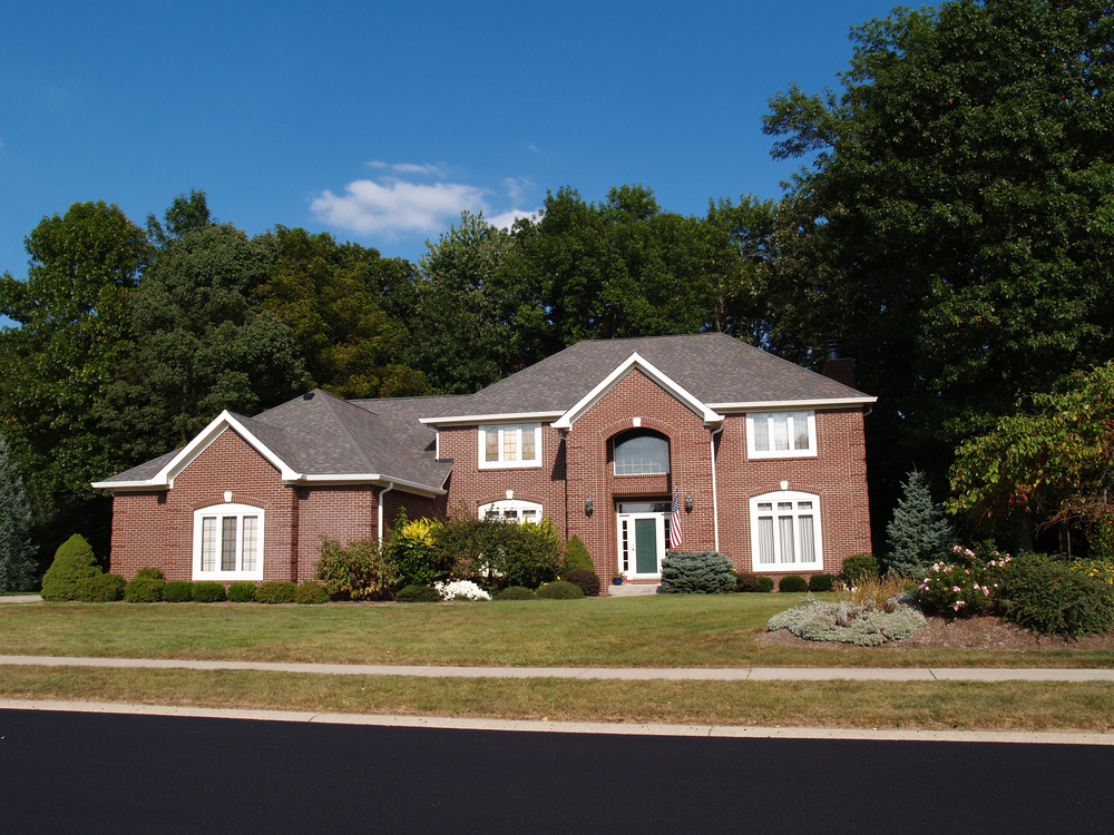 Two-story red-brick home with multi-gabled roofline and arched central entryway