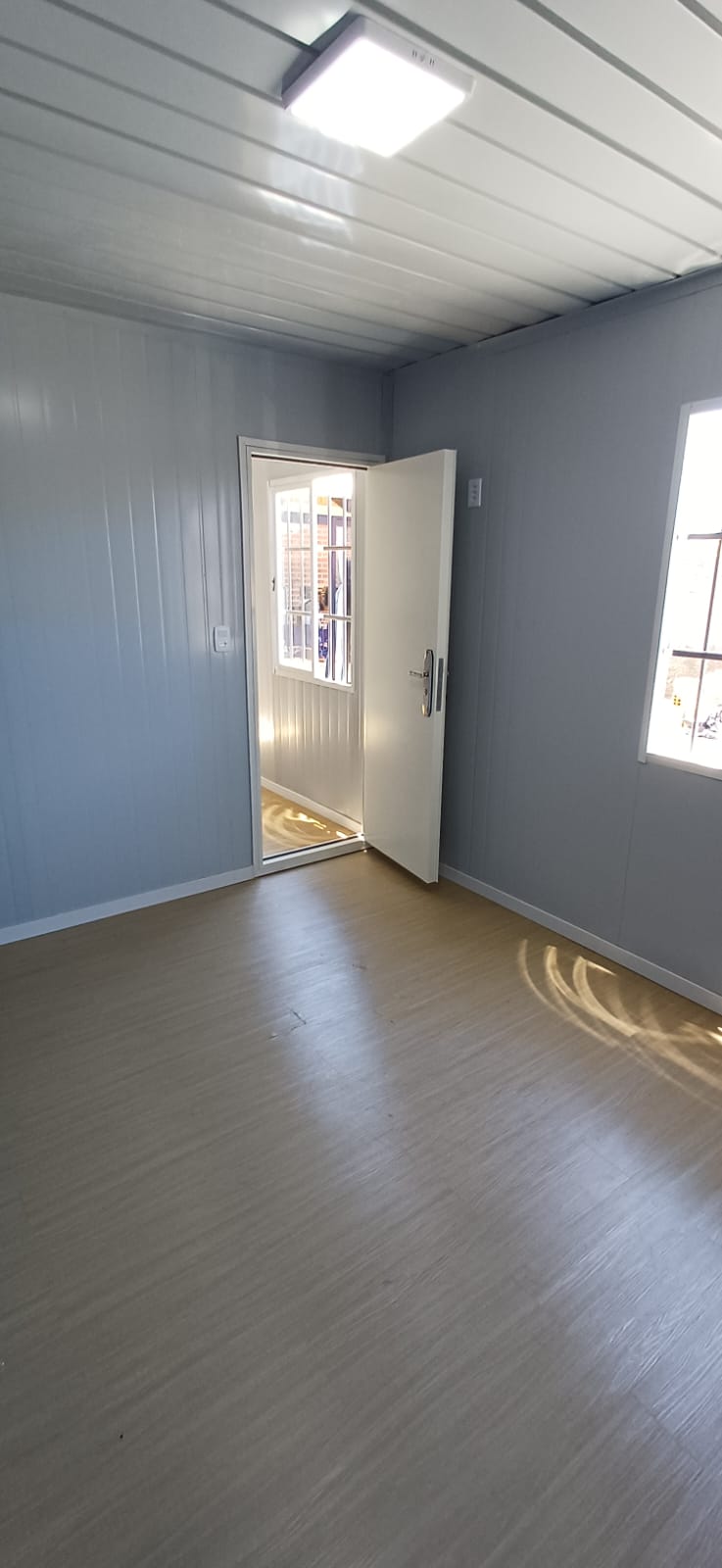 Vista da porta do módulo com os ambientes de sala e cozinha integrados