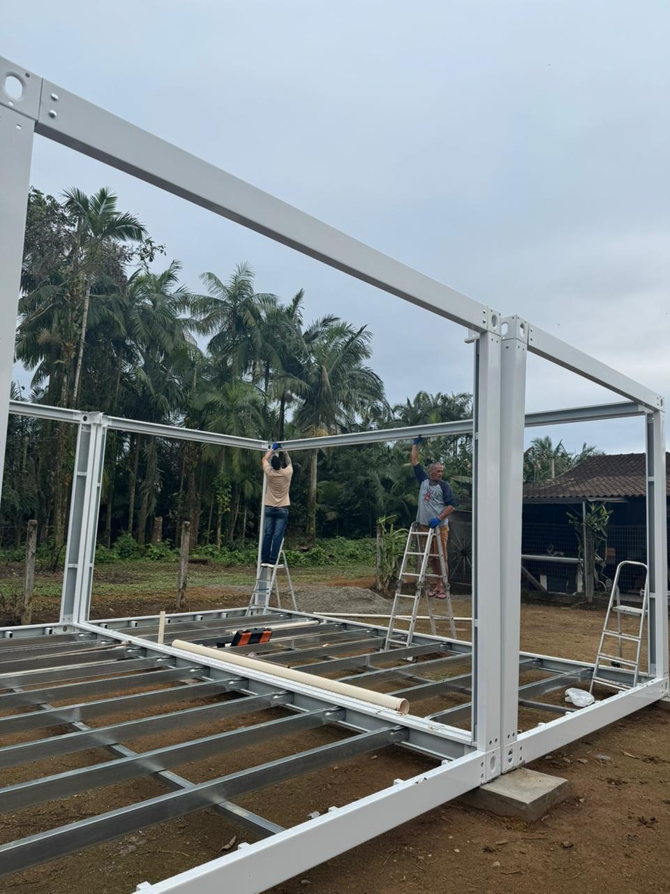 Trabalhadores fixando as vigas superiores da estrutura metálica do módulo