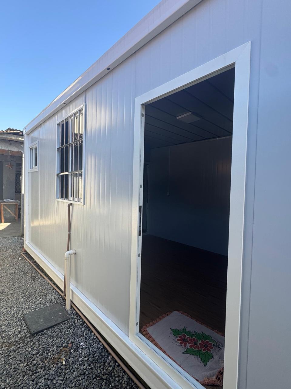 Kitnet modular 3x6 com porta aberta mostrando o piso laminado interno