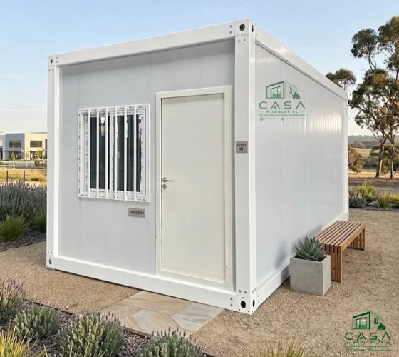 Casa container 3x6m externa, branca, com porta central, janela com grades e banco de madeira