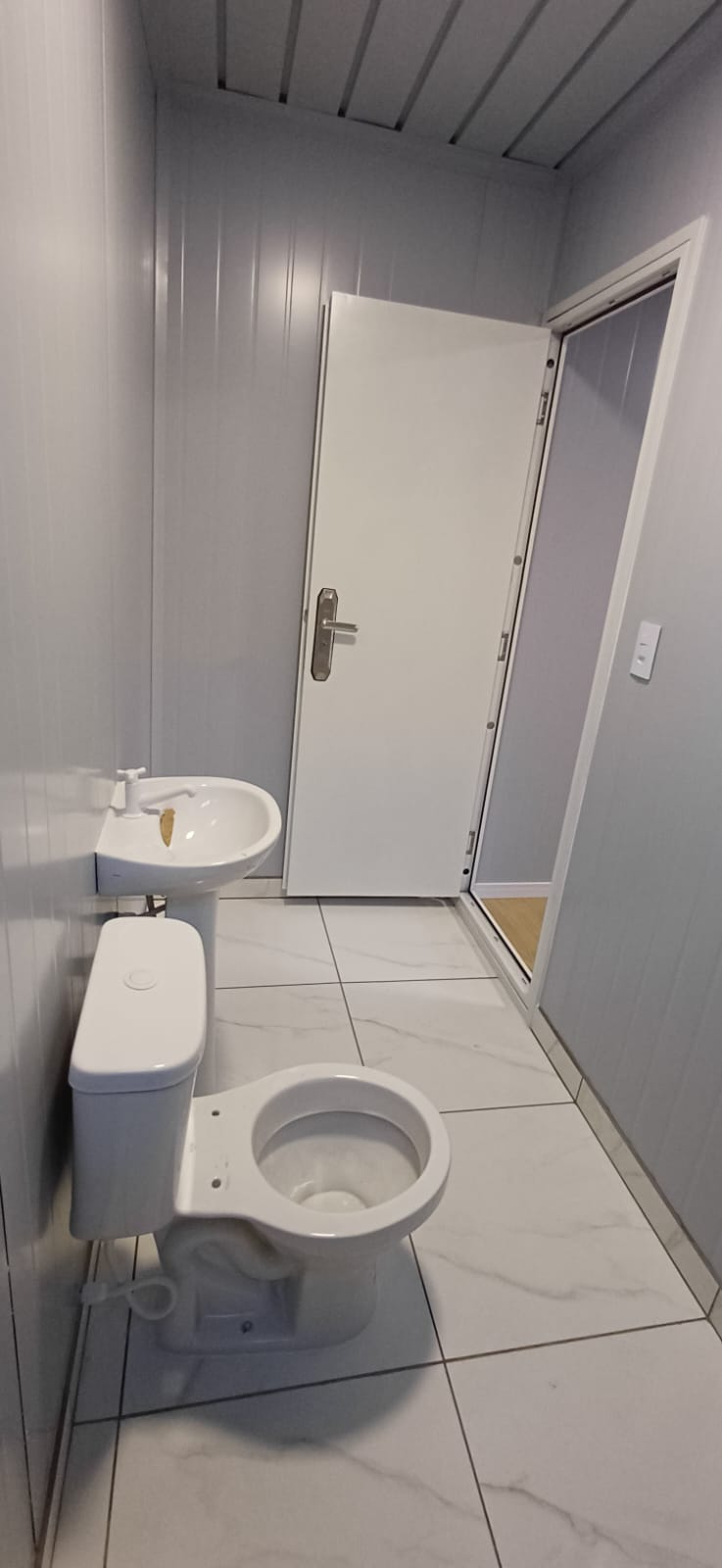 Banheiro do módulo modular 3x7 em Itapema com louças brancas e piso de porcelanato
