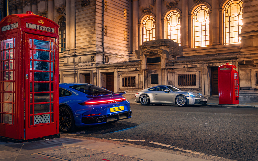 Blue and silver Porsche 911 models beside red telephone boxes in London, marking Porsche’s 75th anniversary in the UK