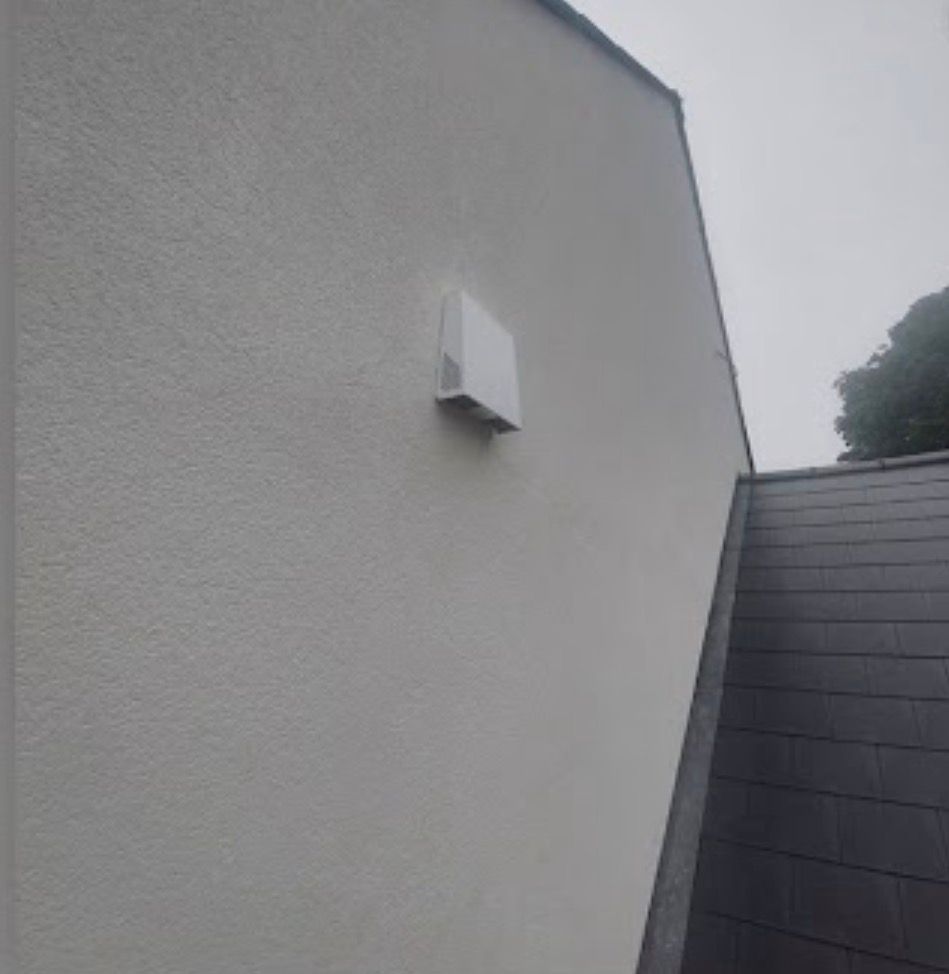 Off-white thin coat render wall with exterior vent and adjoining roof tiles