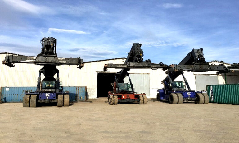 Reach stackers estacionados em frente ao galpão