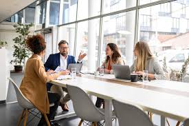 A professional team meeting around a conference table in a bright modern office with floor-to-ceiling windows