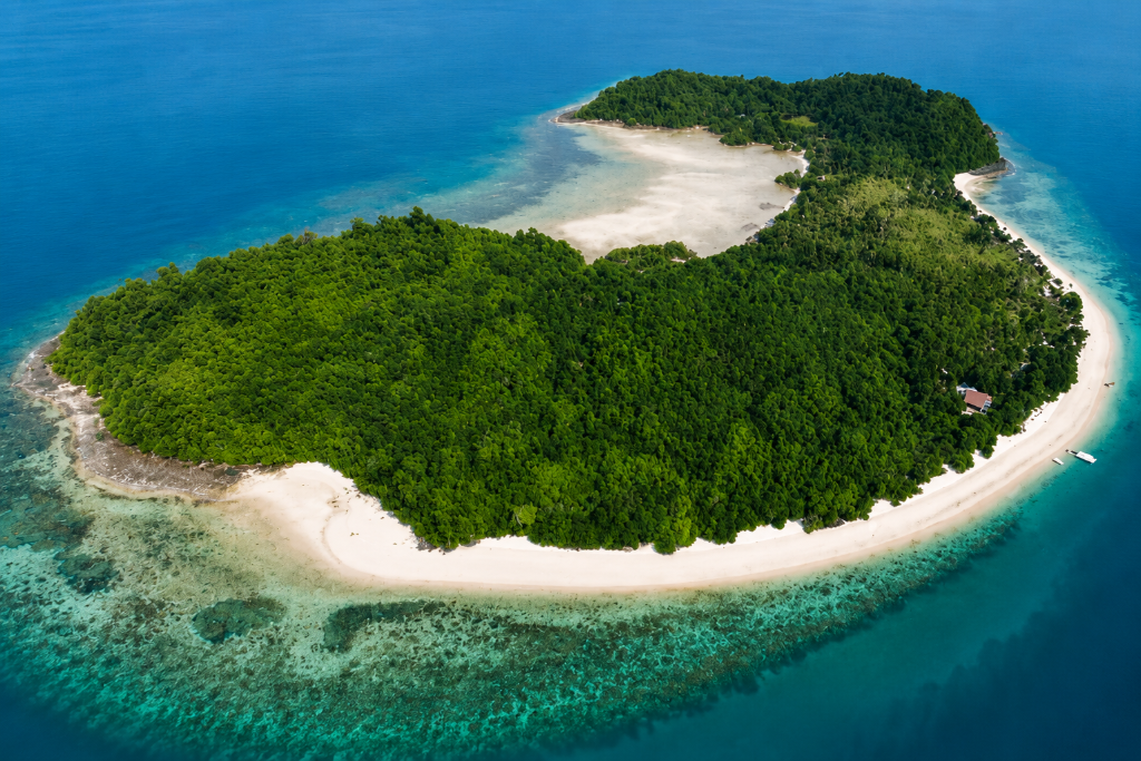 Aerial view of a longtail boat in crystal clear turquoise waters of the Andaman Sea