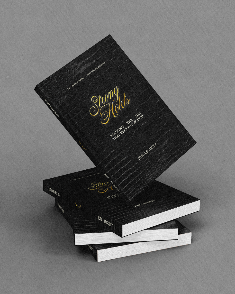 Strong Holds devotional — black textured hardcover with gold script title, shown as a stack of copies