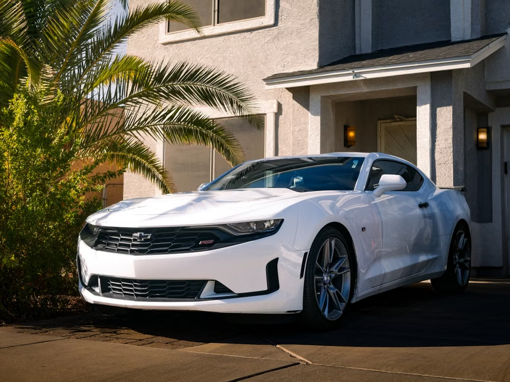 White Chevrolet Camaro parked in a residential driveway during a mobile detail