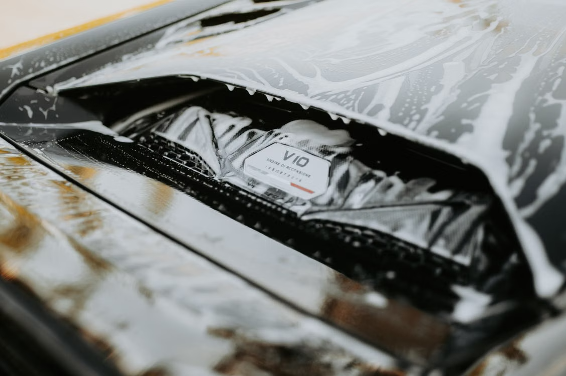 V10 engine bay plaque covered in white soap suds during a detail