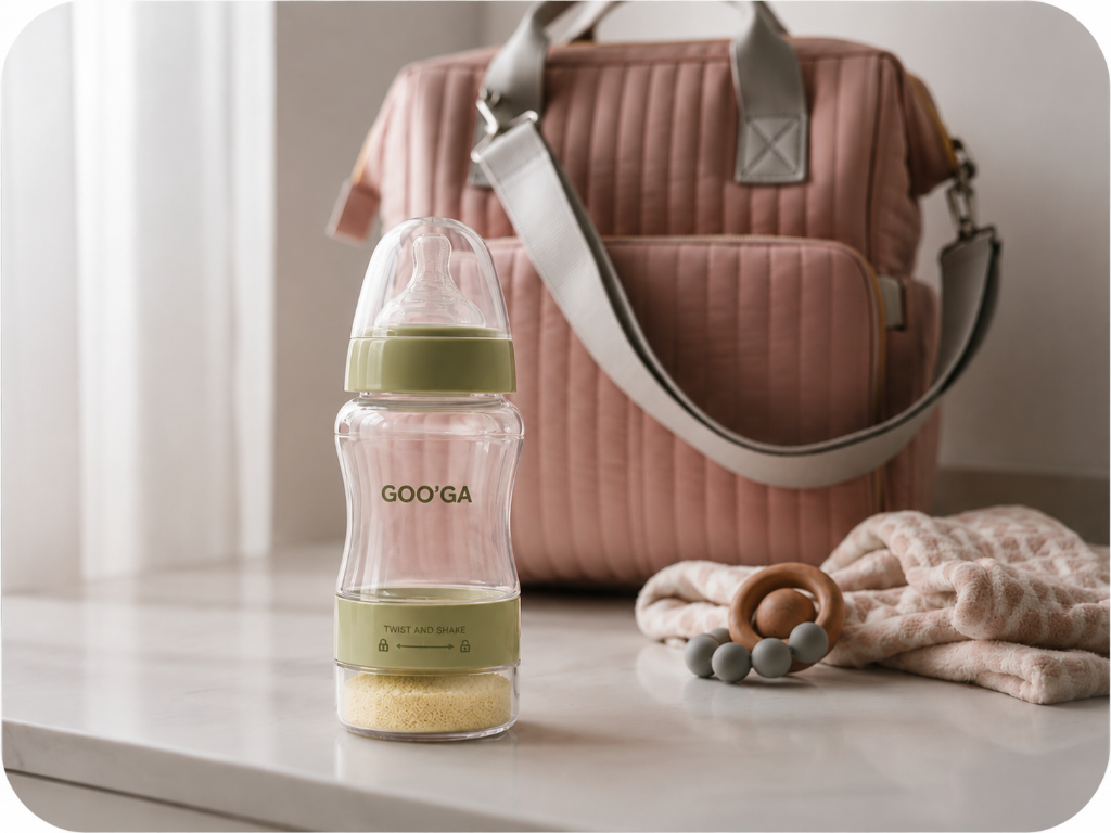 Goo'Ga baby bottle with sage green accents on a clean white surface with a diaper bag