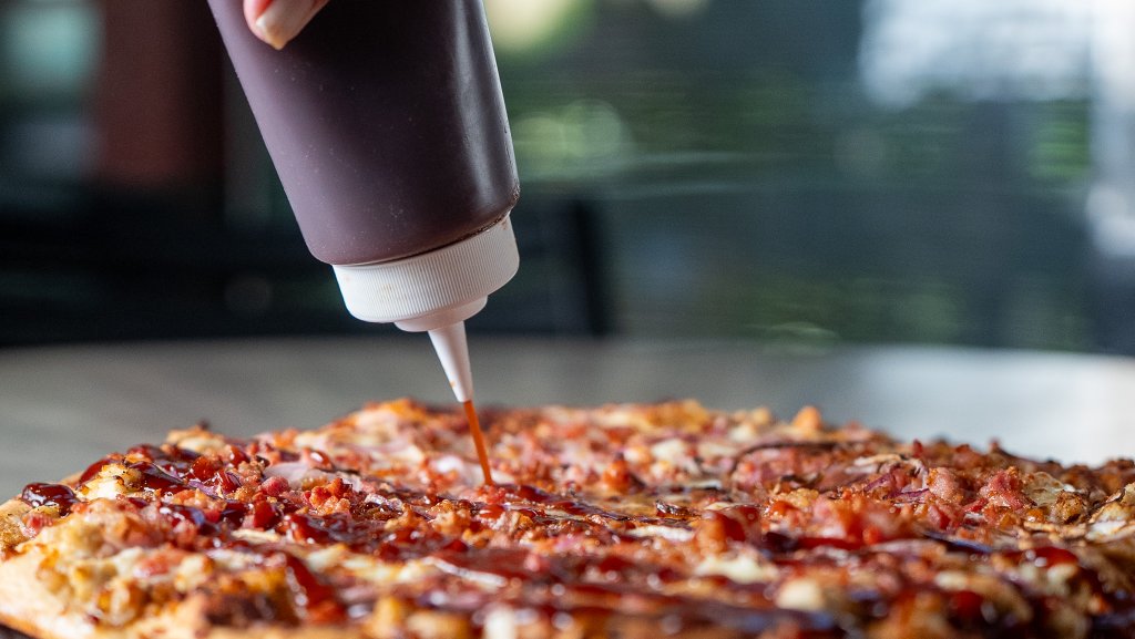 Drizzling BBQ sauce on pizza