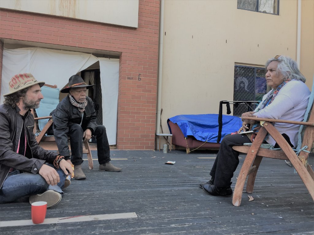 Three people in discussion on a wooden deck