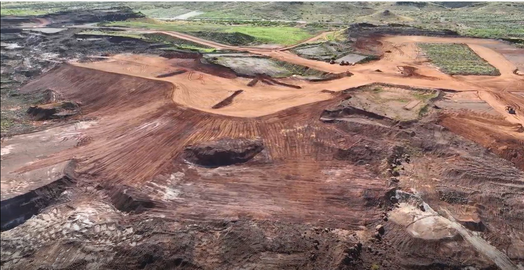 Aerial view of tiered excavations and tracked red earth on a Pilbara site