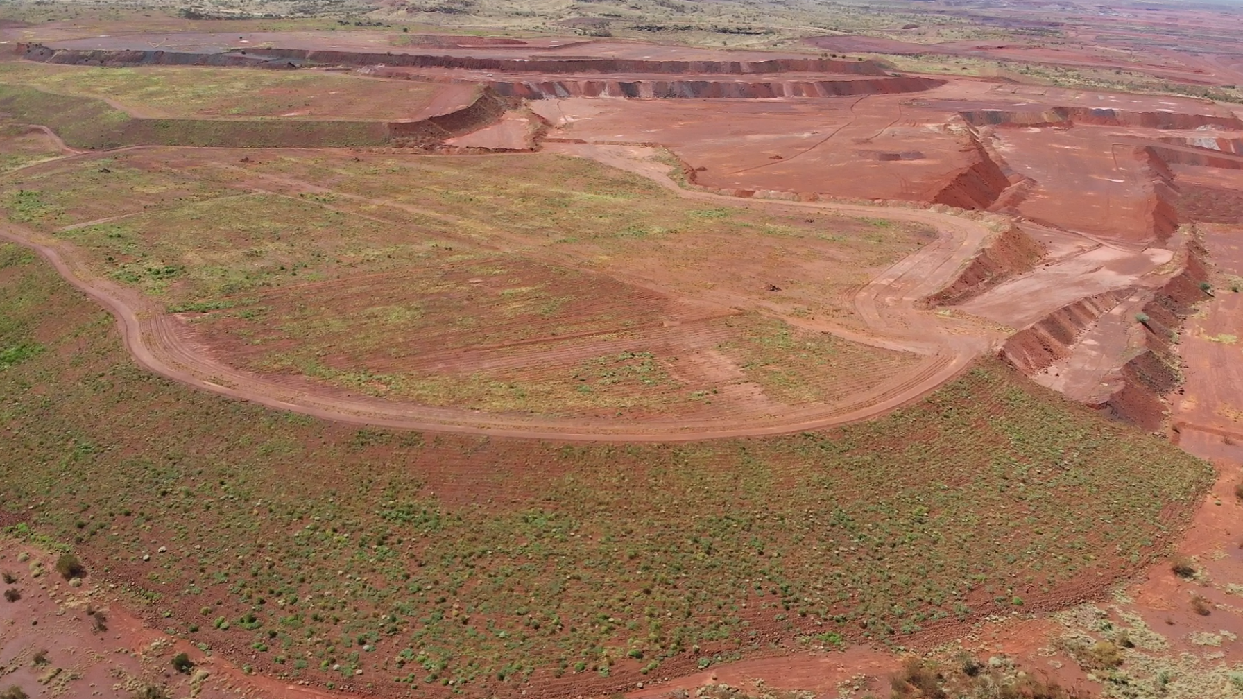 Aerial view of a rehabilitated block with revegetation beside open-cut workings in the Pilbara