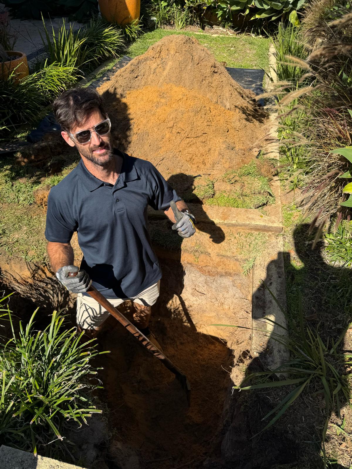 Checkmate Plumbing tradesman on-site in a garden trench