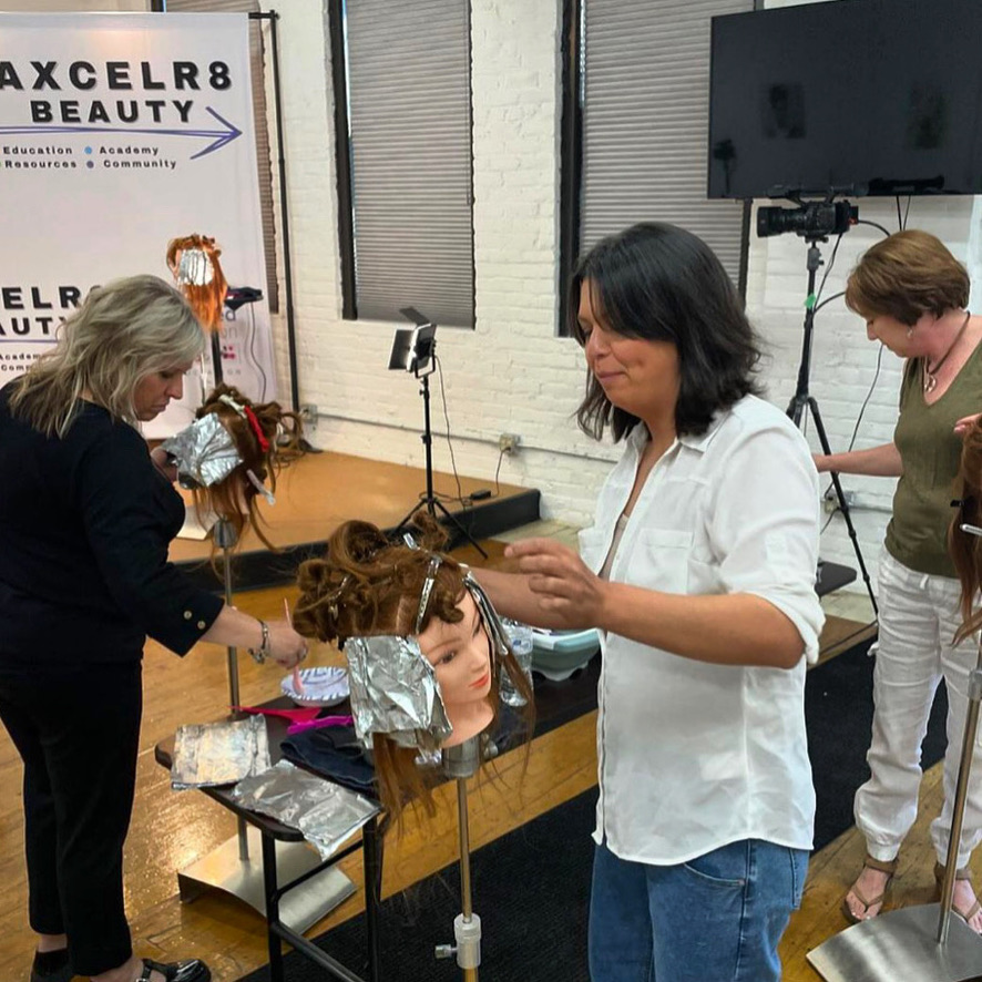 Stylist working on a mannequin head in the Axcelr8 Beauty academy studio