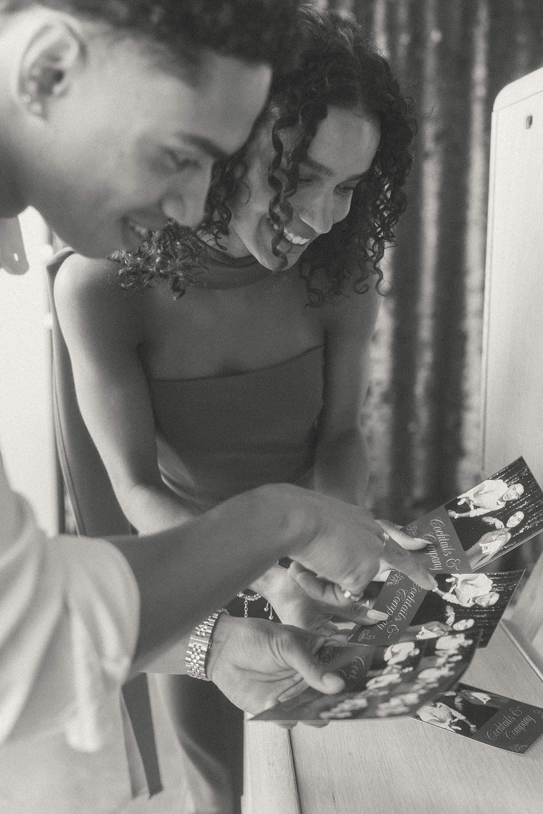 A couple looking at their photo booth prints in black and white