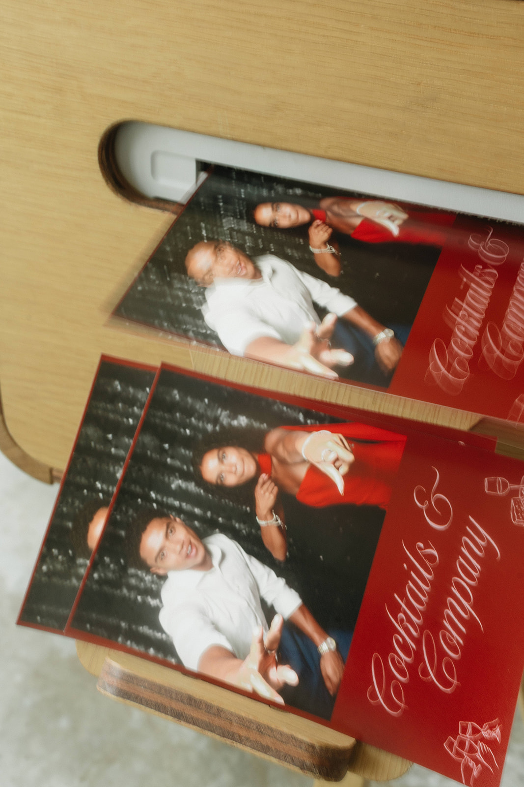 Photo booth prints emerging from a wooden photo booth kiosk