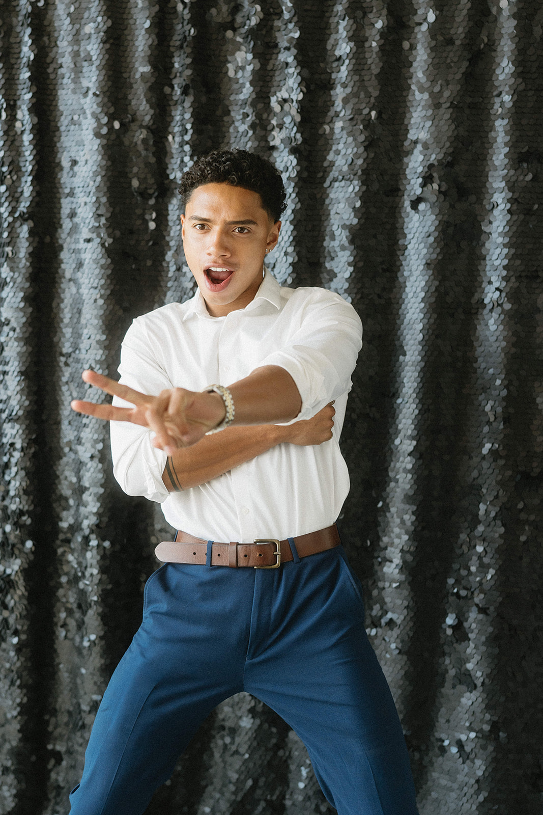 A guest posing in front of a black sequin backdrop at a photo booth
