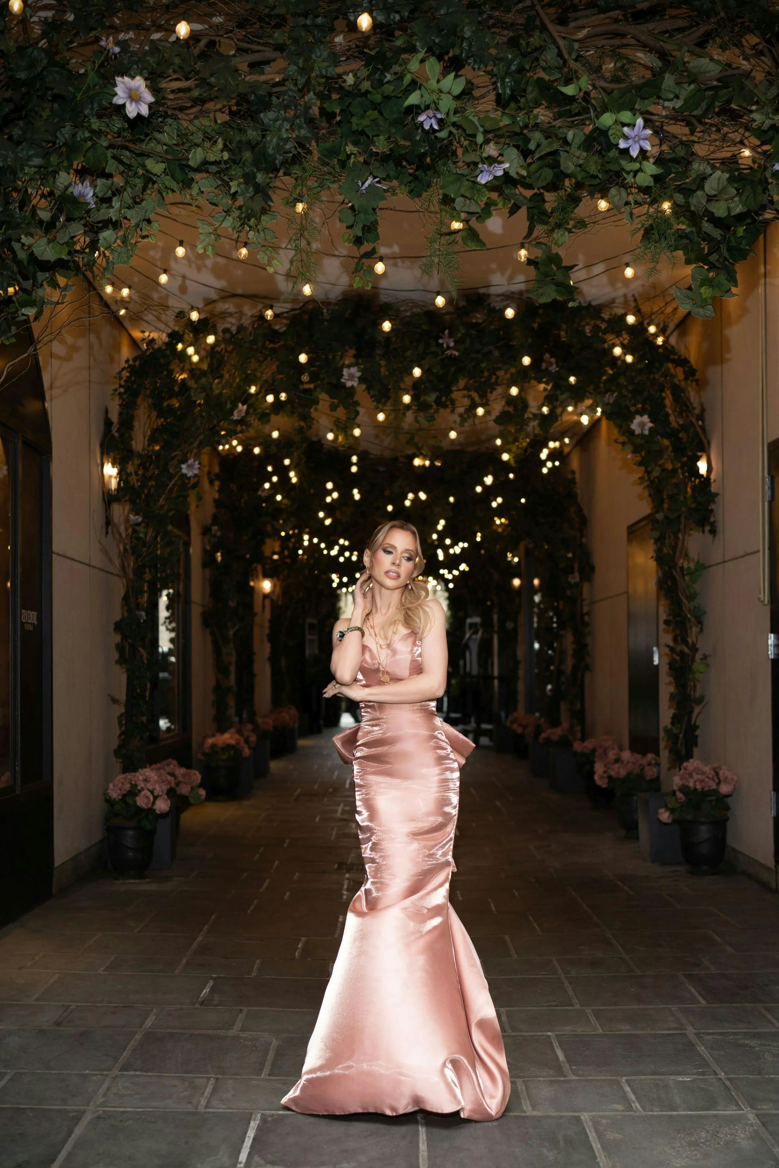 Jaimie Hilfiger in a rose pink liquid satin mermaid gown under string lights, styled by Laura Rudovic for L'Officiel Baltic