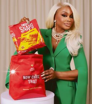 Phaedra Parks in an emerald green suit with pearls and Cheez-It Snap'd Double Cheddar packaging
