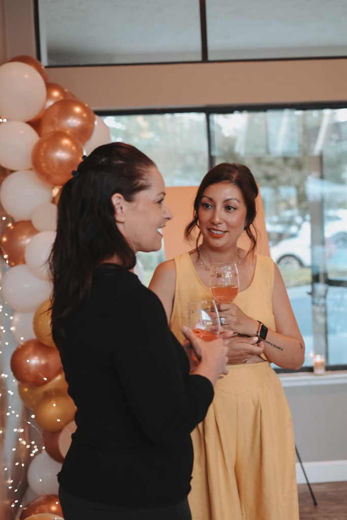 Two women socializing near a balloon arch at a community gathering