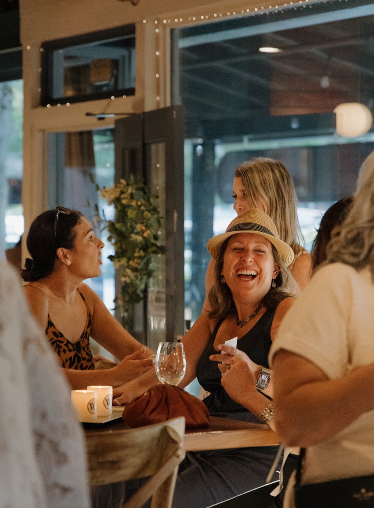 A woman laughing joyfully with friends at a gathering