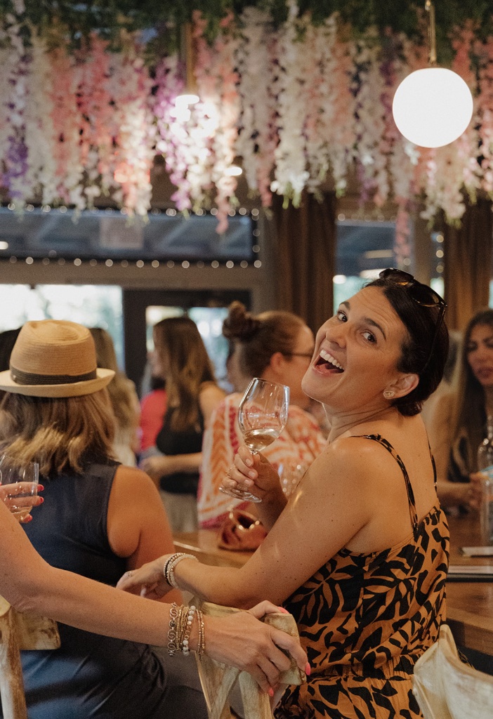 A woman smiling with a glass of wine at a She Connects event