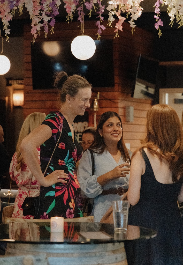 Three women in conversation at an evening community gathering