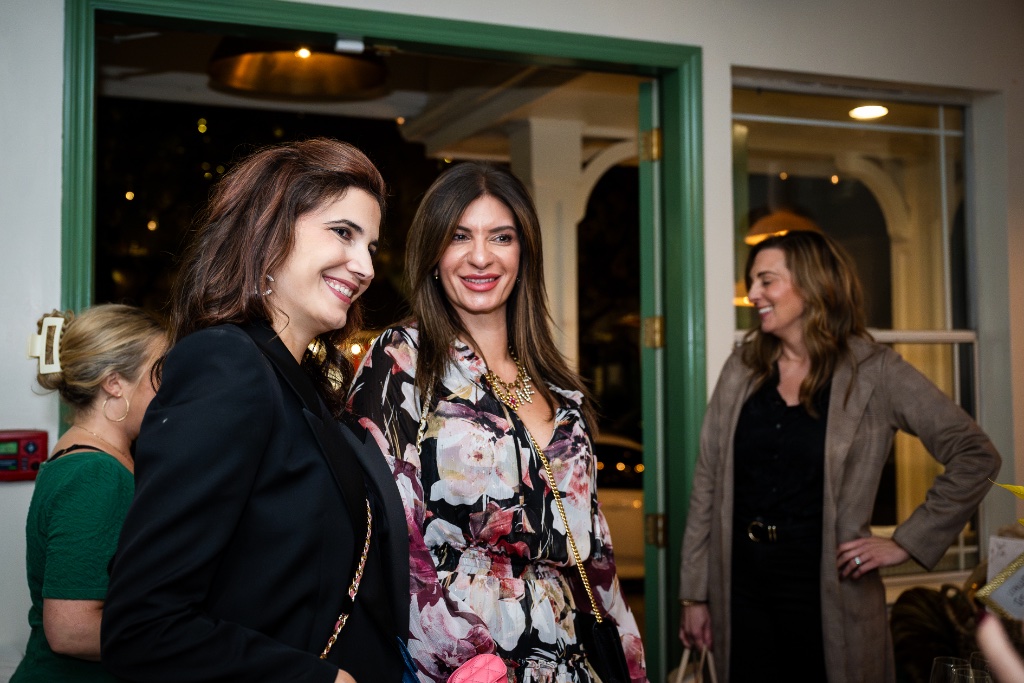 Three women smiling together at an event