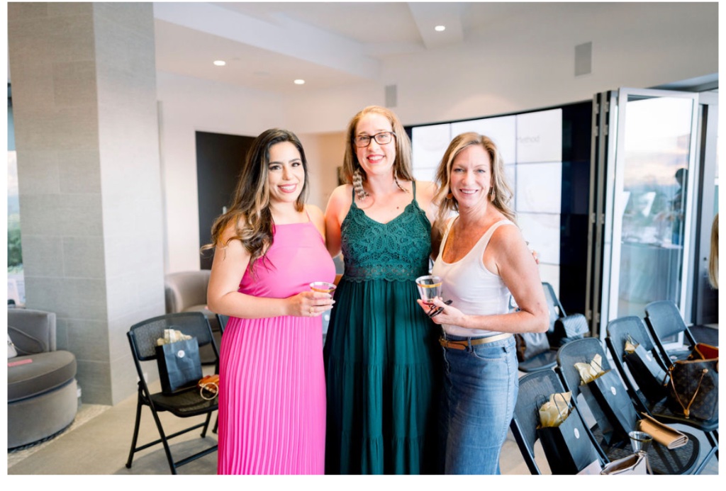 Three friends posing together at an evening event