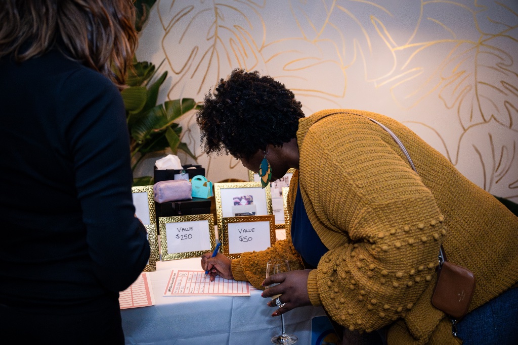 A woman bidding at a silent auction during a She Connects event