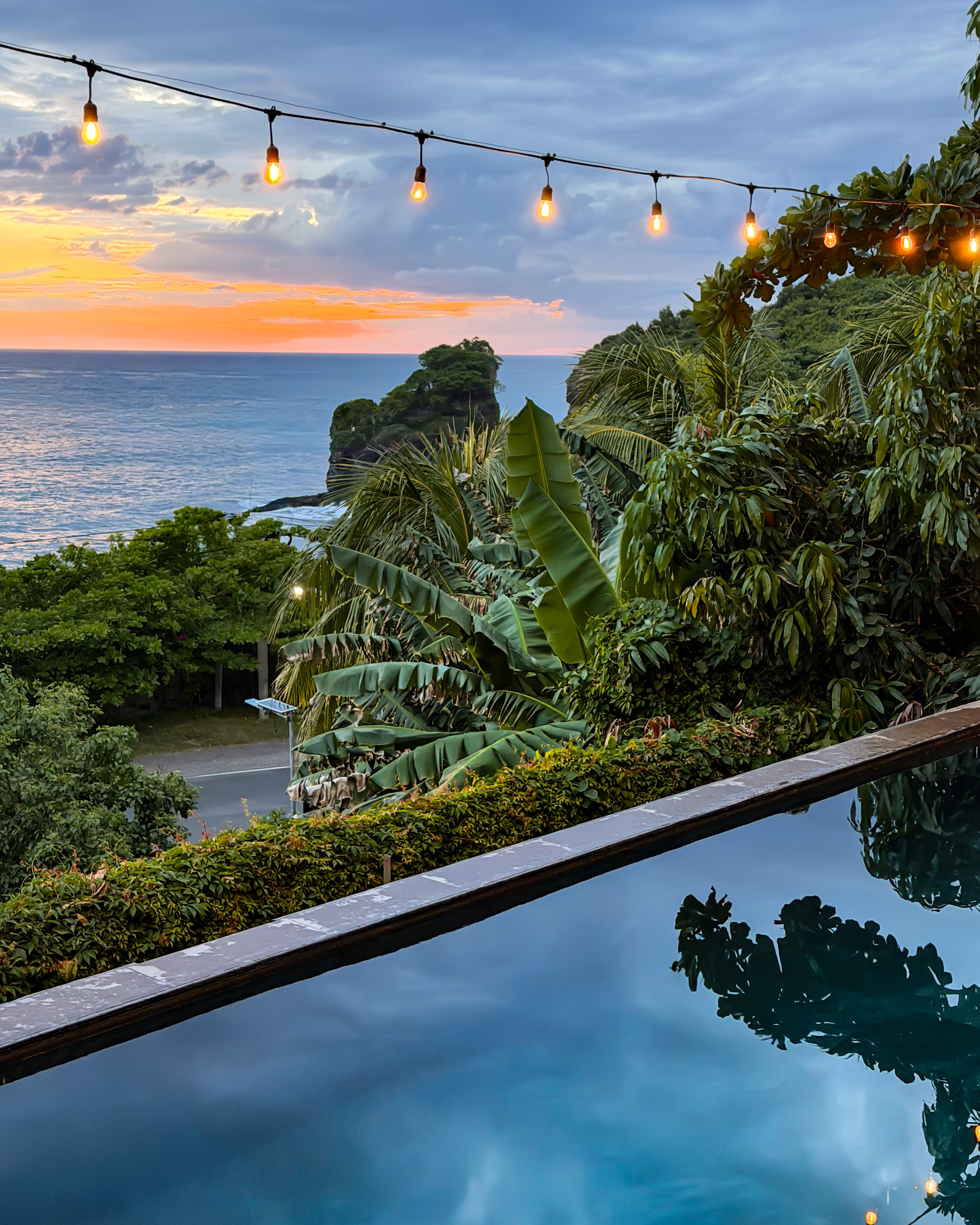 Infinity pool at sunset with string lights