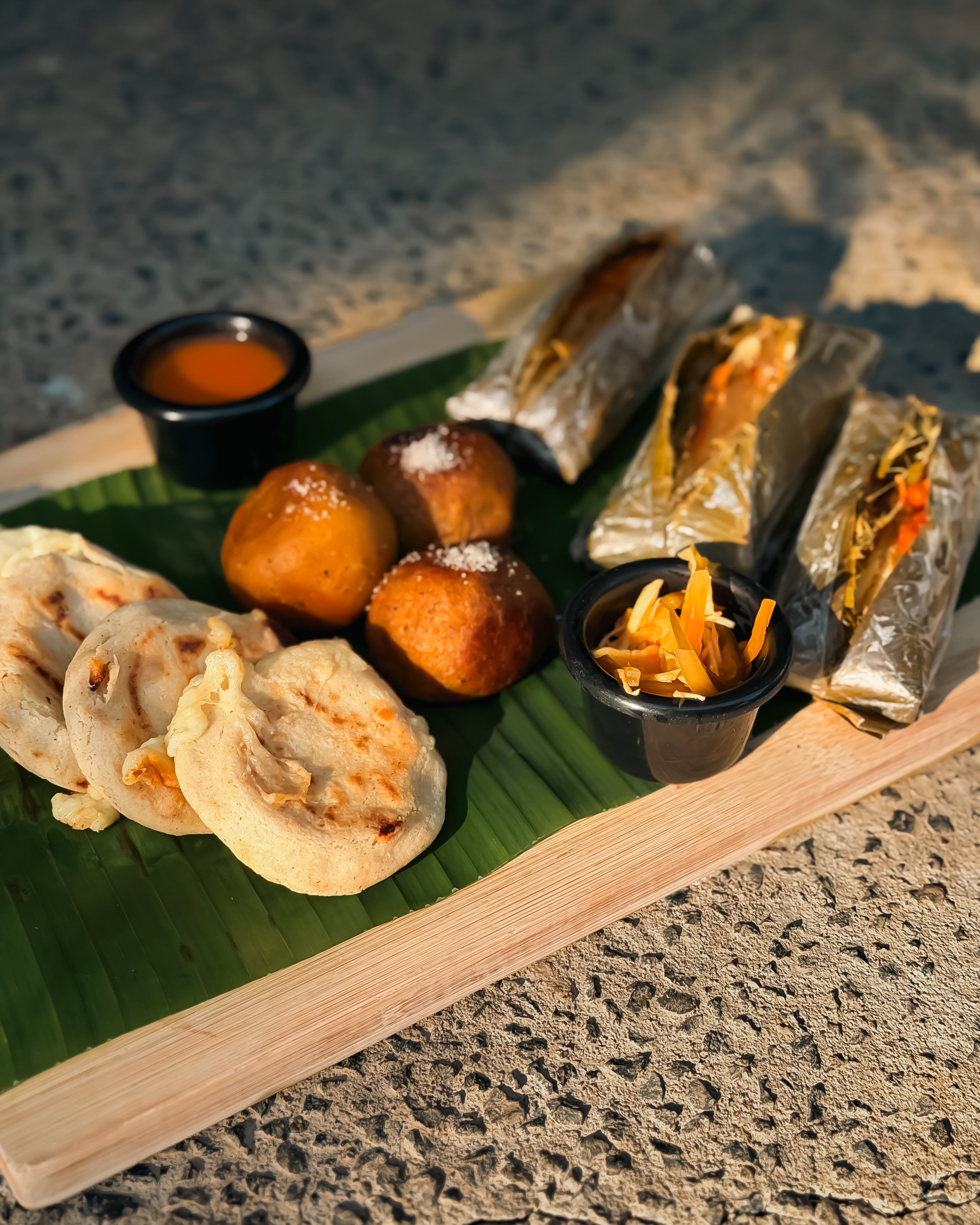 Pupusas, fritters and tamales on a banana leaf