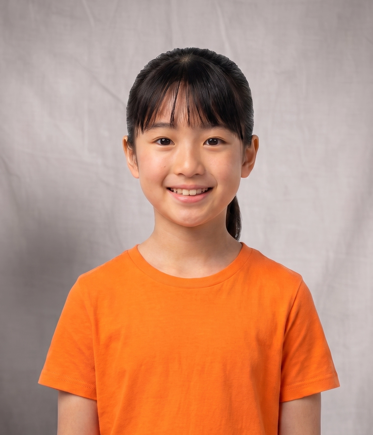 Head-and-shoulders portrait of Naomi, a smiling middle-grade girl with dark hair pulled back, straight bangs, and an orange T-shirt.